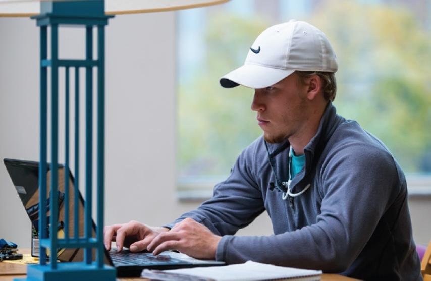 Student sitting in the library working on a laptop